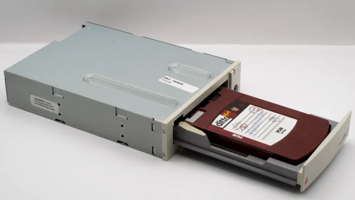 Vintage computer backup tape drive with open tray, showcasing retro technology.