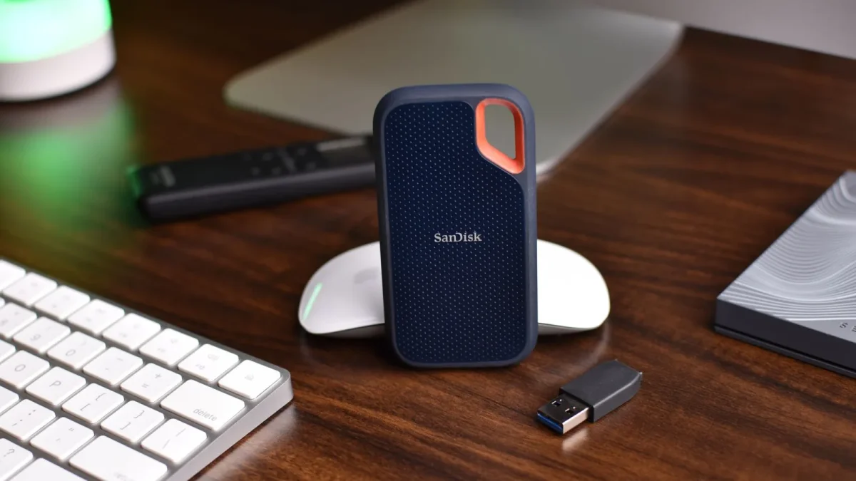 Close-up of a desk setup featuring a SanDisk SSD, keyboard, and USB drive, highlighting modern technology.