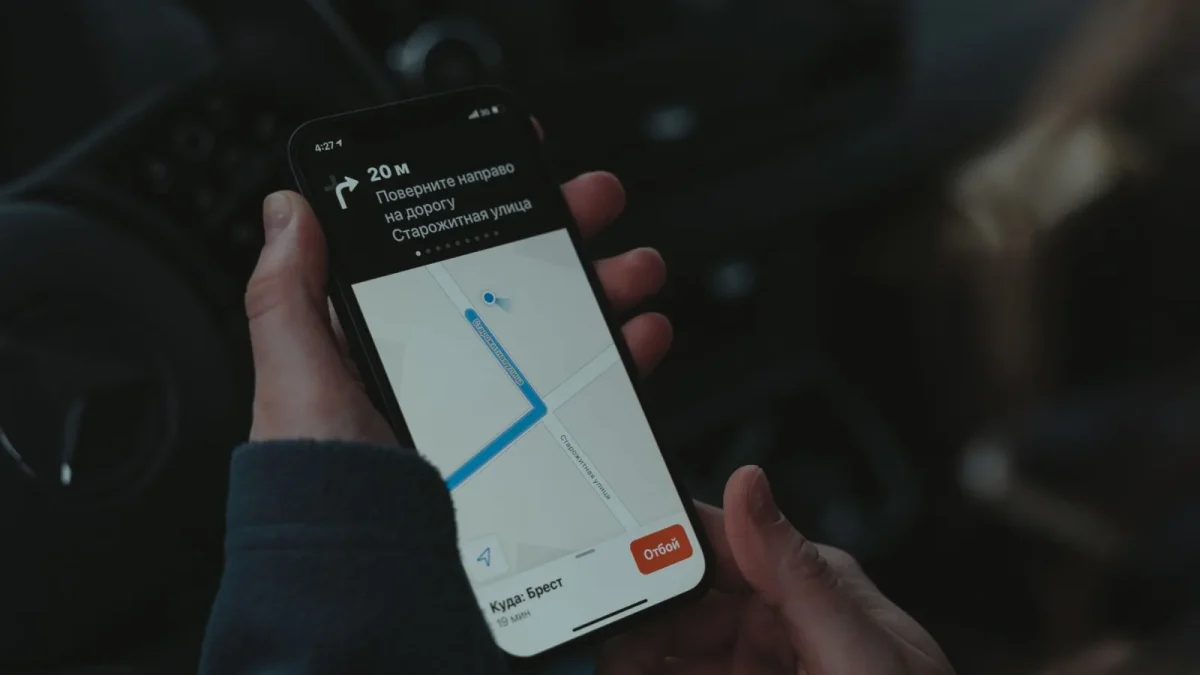 Close-up of a smartphone displaying a navigation app in a car, highlighting modern technology use while driving.