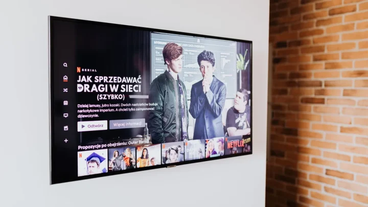 Smart TV displaying streaming content in modern living room setting with exposed brick wall.