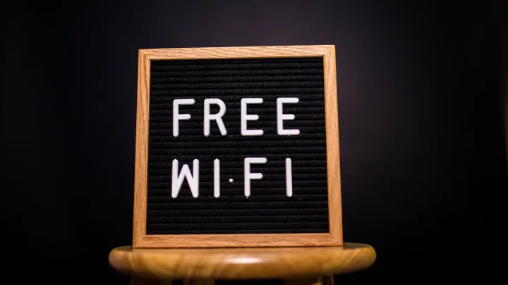 A wooden frame sign with 'Free Wi-Fi' text displayed on a stool in a dark room.