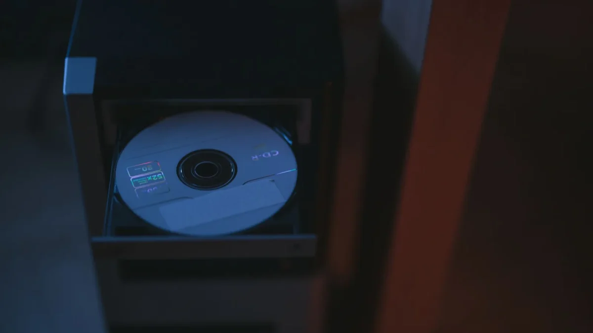 A close-up image of a CD partially ejected from a drive, showcasing soft lighting.