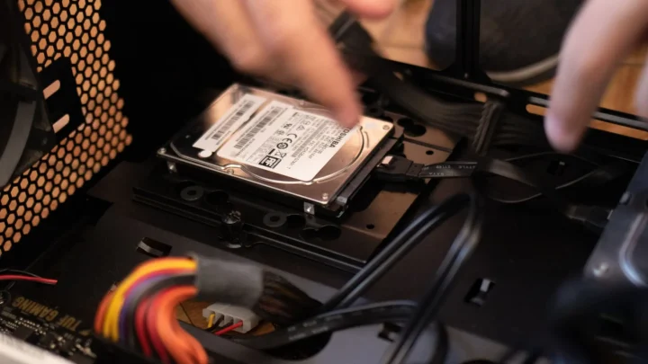 Hands installing a hard drive in a computer case, emphasizing technology and connectivity.