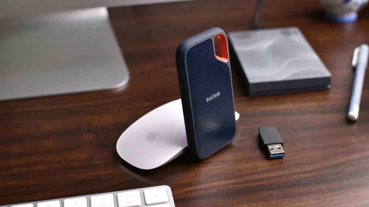 Close-up of a modern desk setup with a SanDisk external hard drive and electronics on a wooden surface.