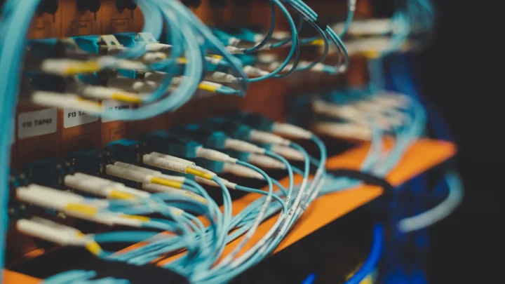 Closeup of many cables with blue wires plugged in modern switch with similar adapters on blurred background in modern st
