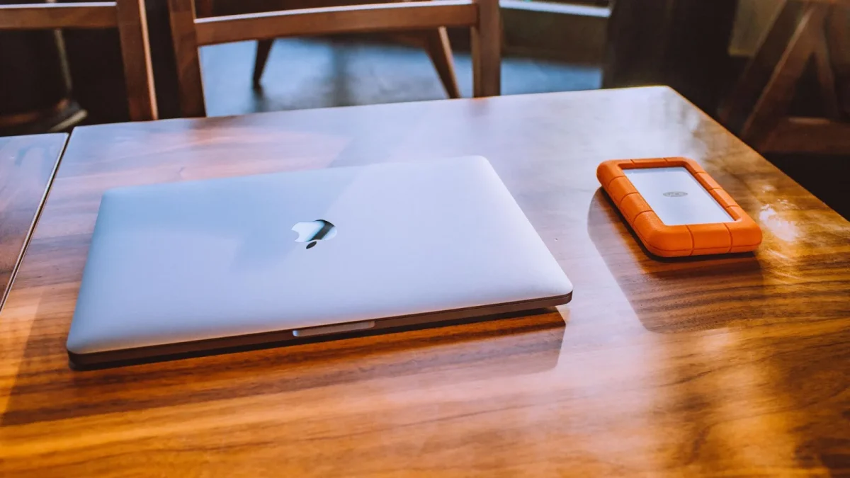 A sleek laptop and rugged external drive on a stylish wooden table in a contemporary indoor setting.