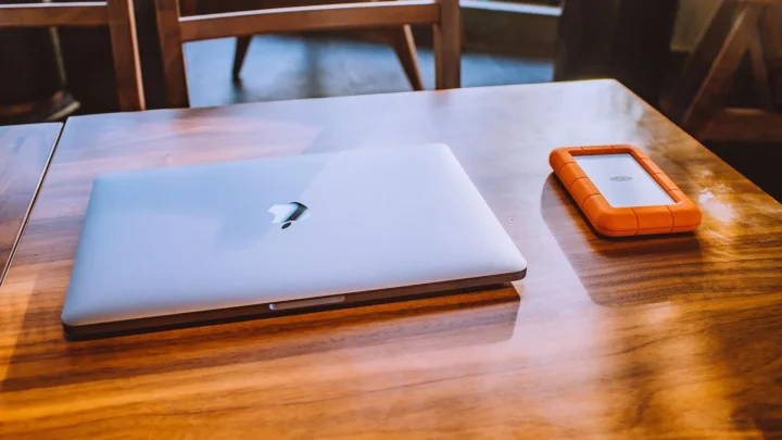 A sleek laptop and rugged external drive on a stylish wooden table in a contemporary indoor setting.
