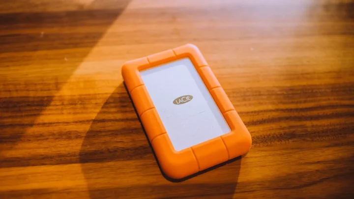 Close-up of an orange portable hard drive on a wooden table, perfect for tech and business themes.