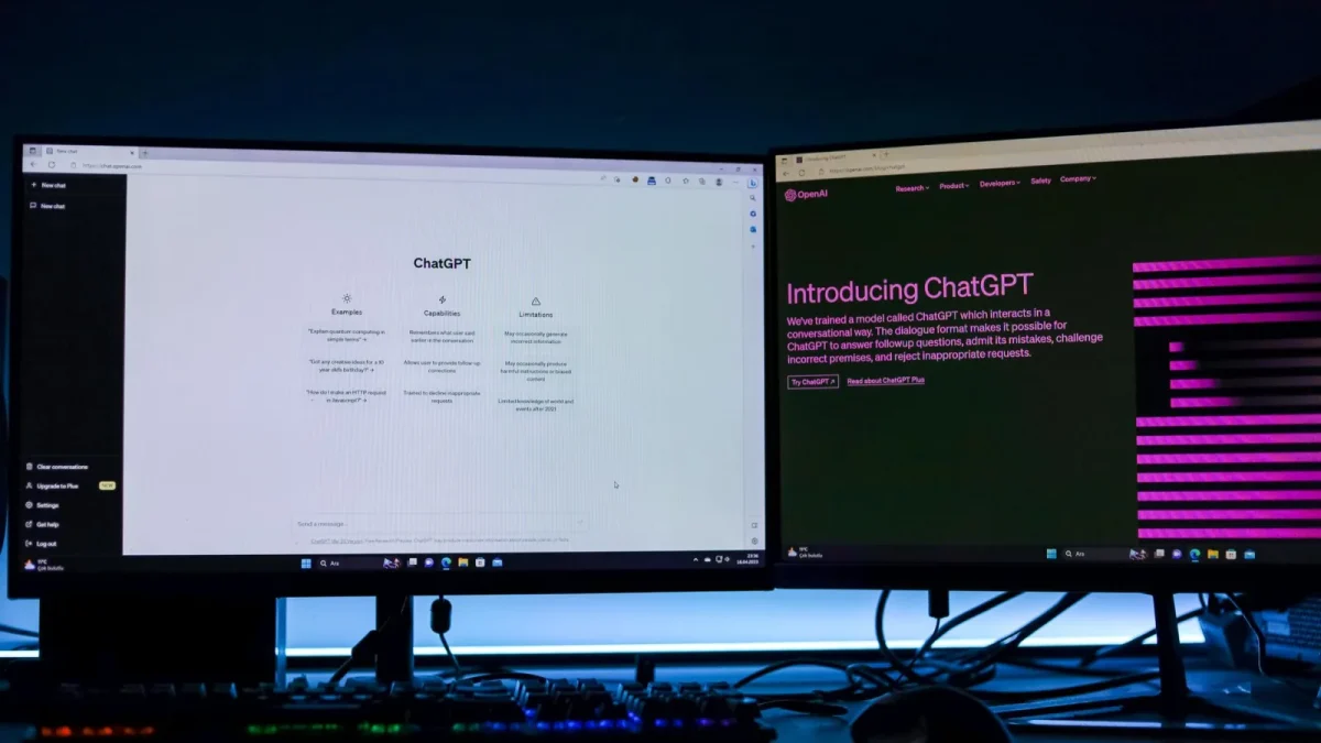 Dual computer monitors showcasing a chat interface in a technology workspace setting.