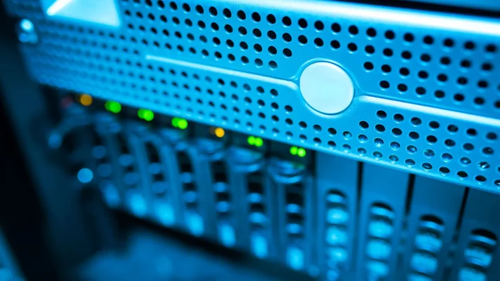 Focused view of a modern data server rack with blinking lights in a blue-lit environment.