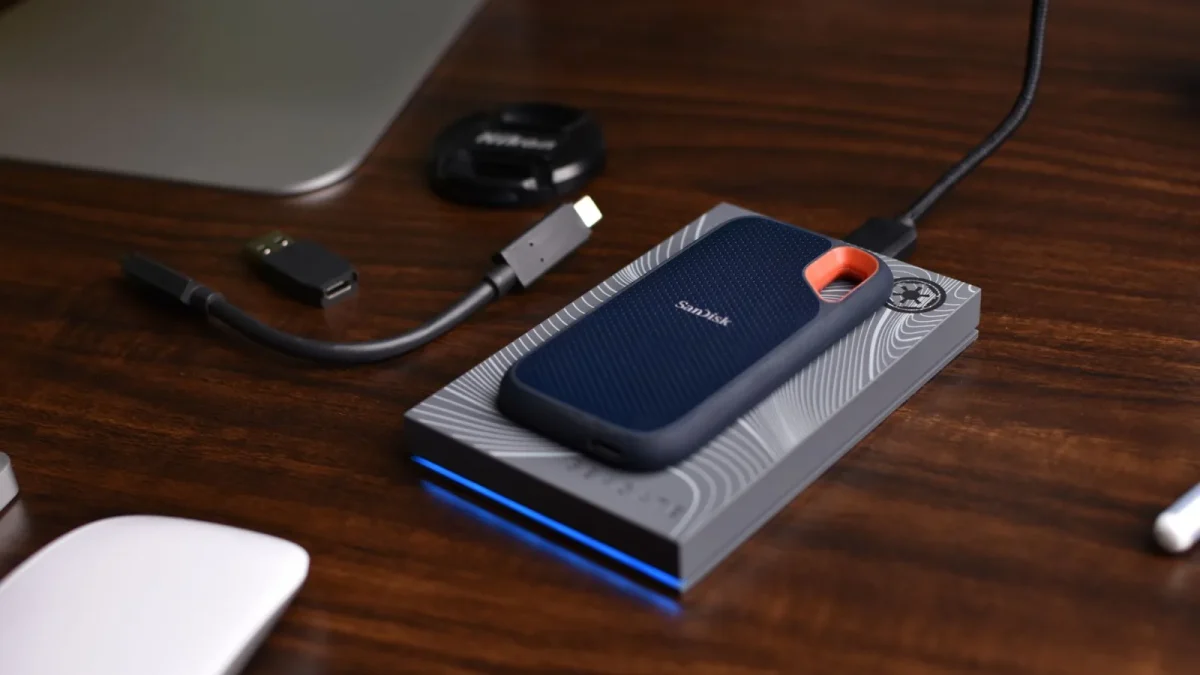 A SanDisk SSD with USB accessories on a wooden desk, showcasing portable technology storage solutions.